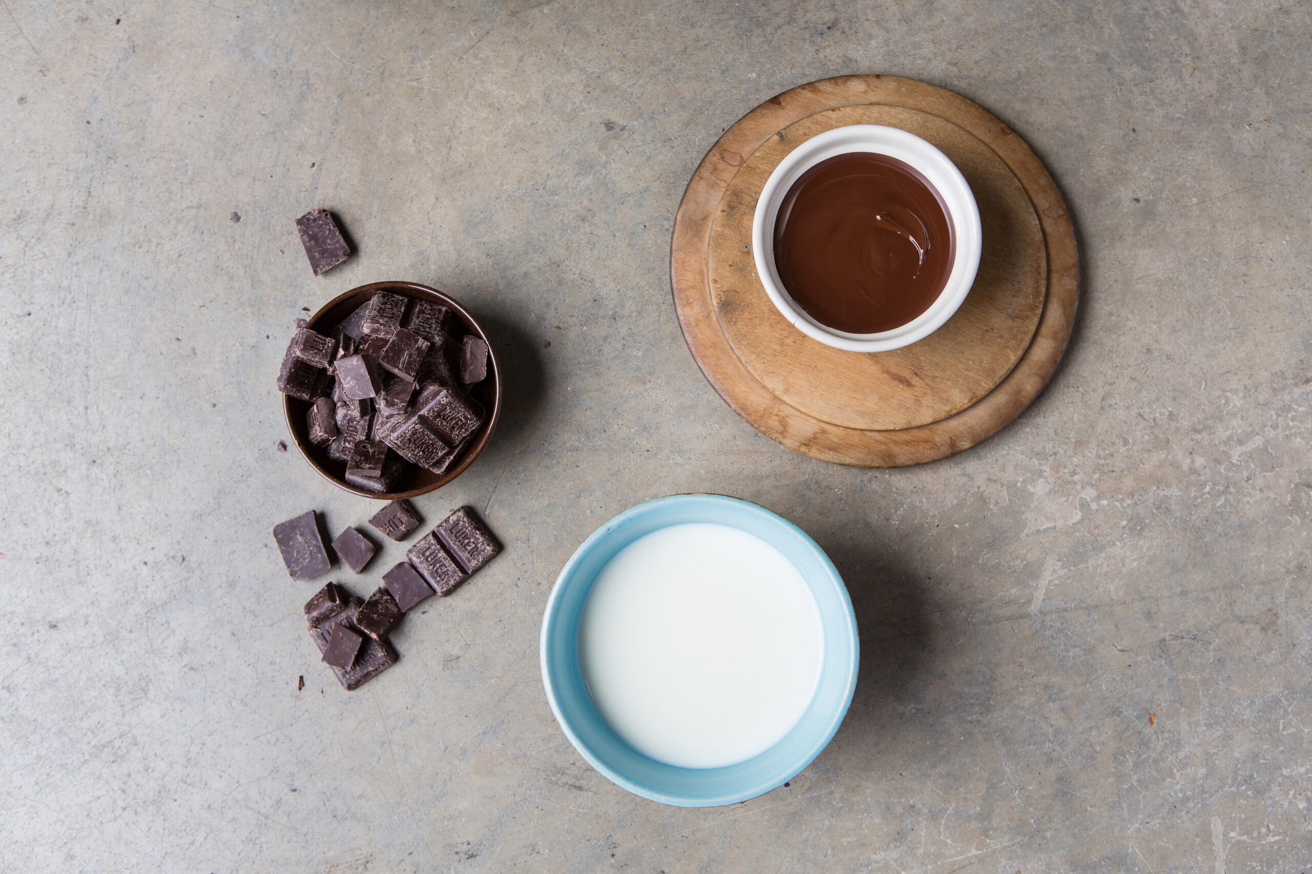 Milk, chocolate, and melted chocolate in bowls on a table