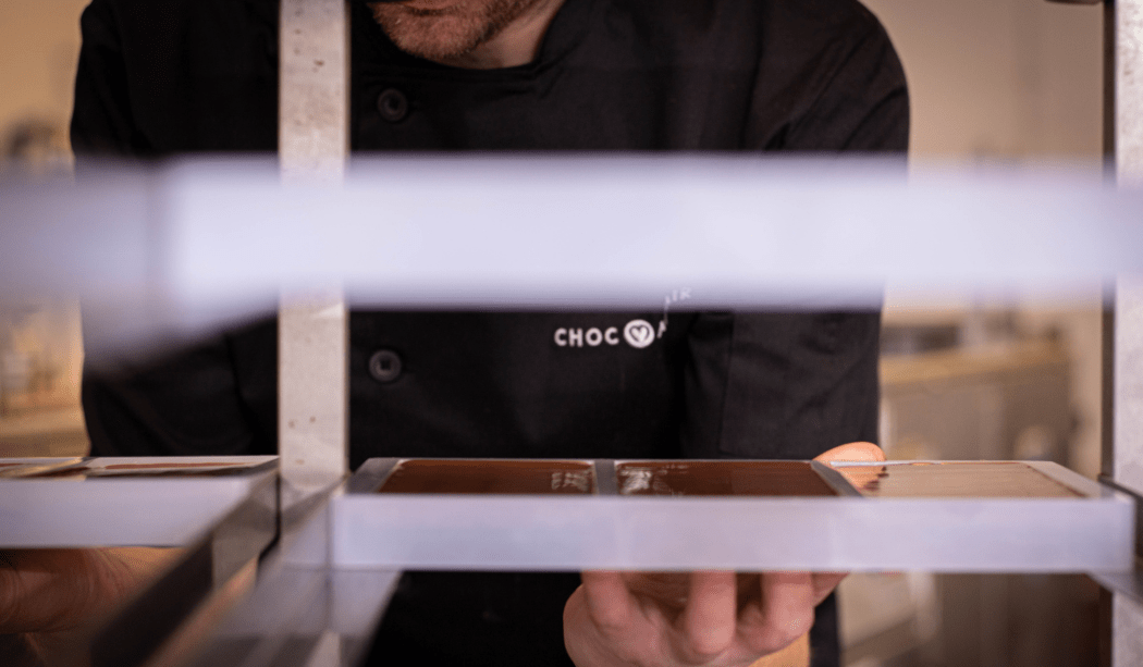 A man wearing a Choc Affair shirt placing chocolate on racks