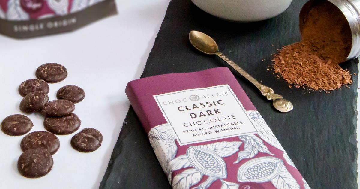 A bar of classic dark chocolate next to chocolate buttons