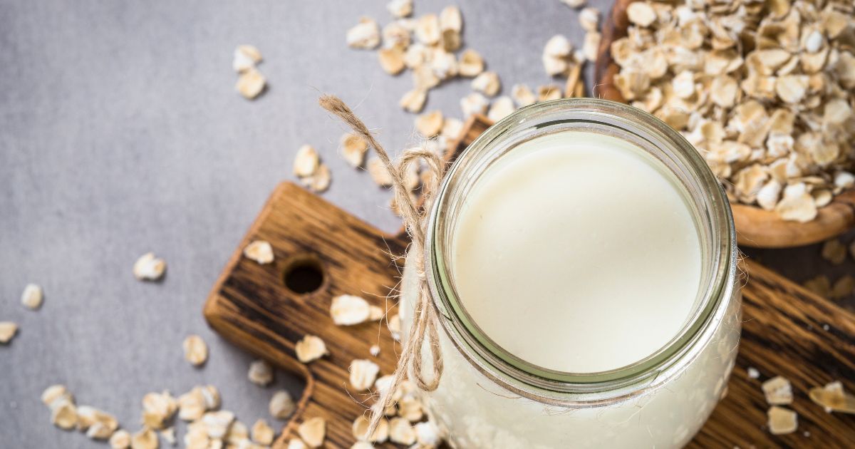 A jar of oat milk next to some oats